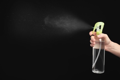 Photo of Woman spraying air freshener on black background, closeup