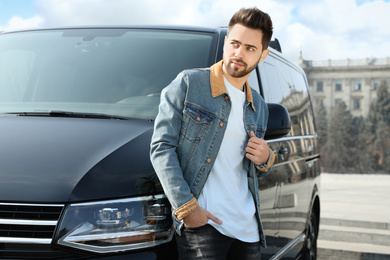 Handsome young man near modern car outdoors