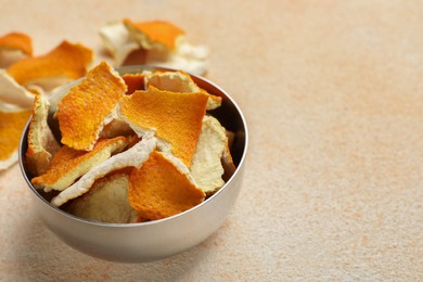 Dry orange peels in bowl on beige table, space for text
