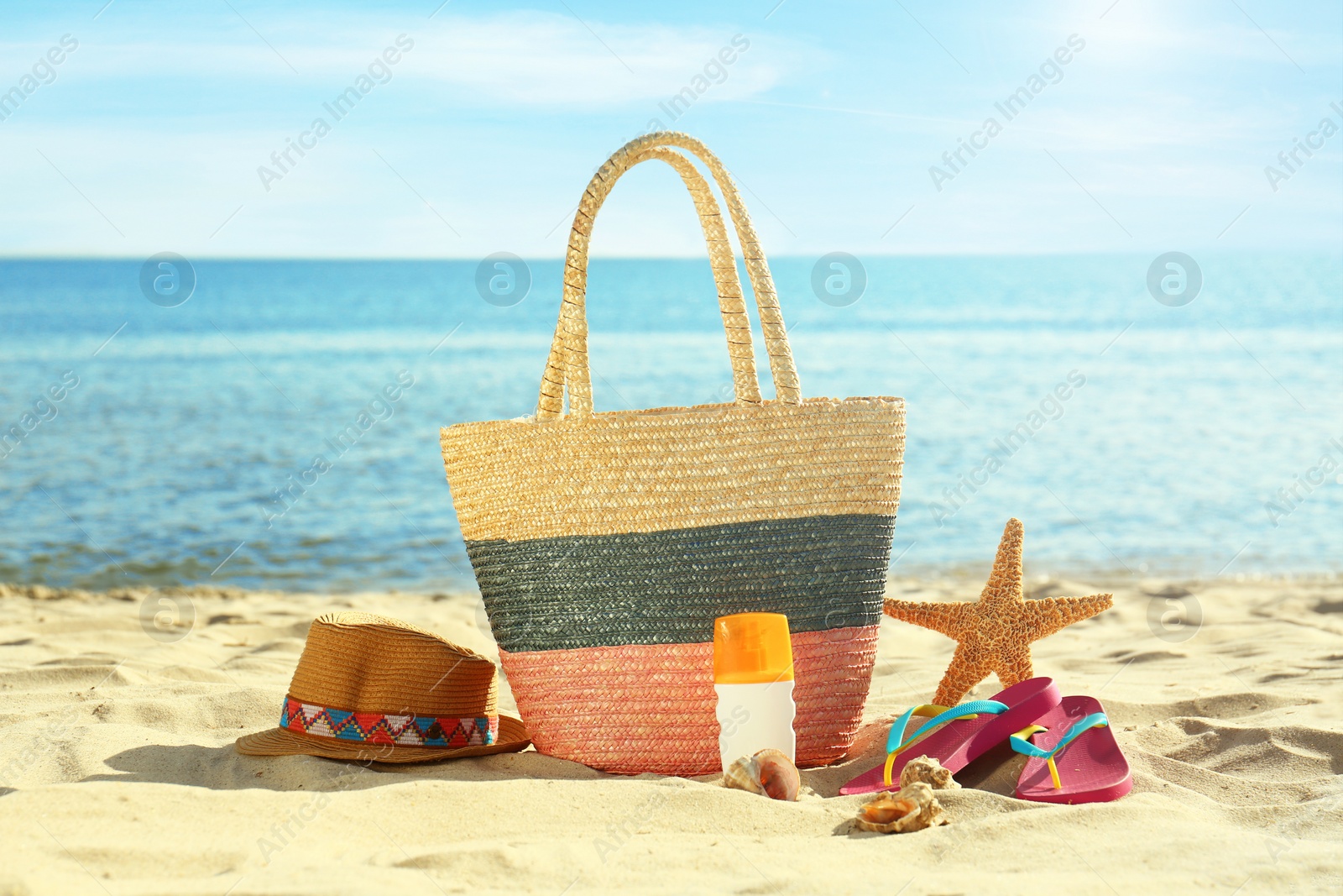 Photo of Composition with stylish beach accessories on sand near sea