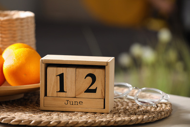 Wooden block calendar and fruits on wicker mat indoors, closeup