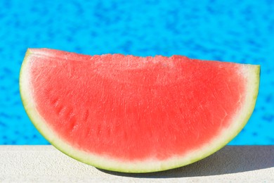 Photo of Slice of fresh juicy watermelon near swimming pool outdoors, closeup