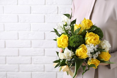 Woman with bouquet of beautiful peony tulips near white brick wall, closeup. Space for text