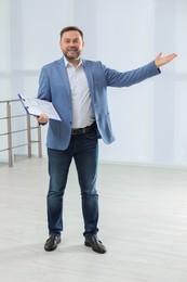 Photo of Male real estate agent with clipboard in new apartment