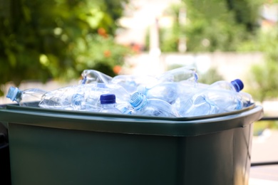 Many used plastic bottles in trash bin outdoors, closeup. Recycling problem