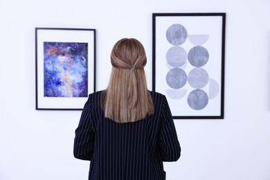 Photo of Young woman at exhibition in art gallery, back view