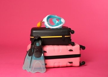 Photo of Stylish suitcases with swimming mask and flippers on color background