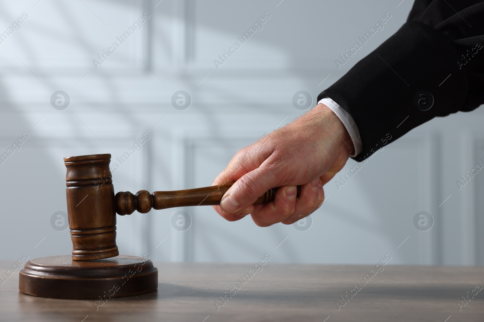 Photo of Judge with gavel at wooden table indoors, closeup