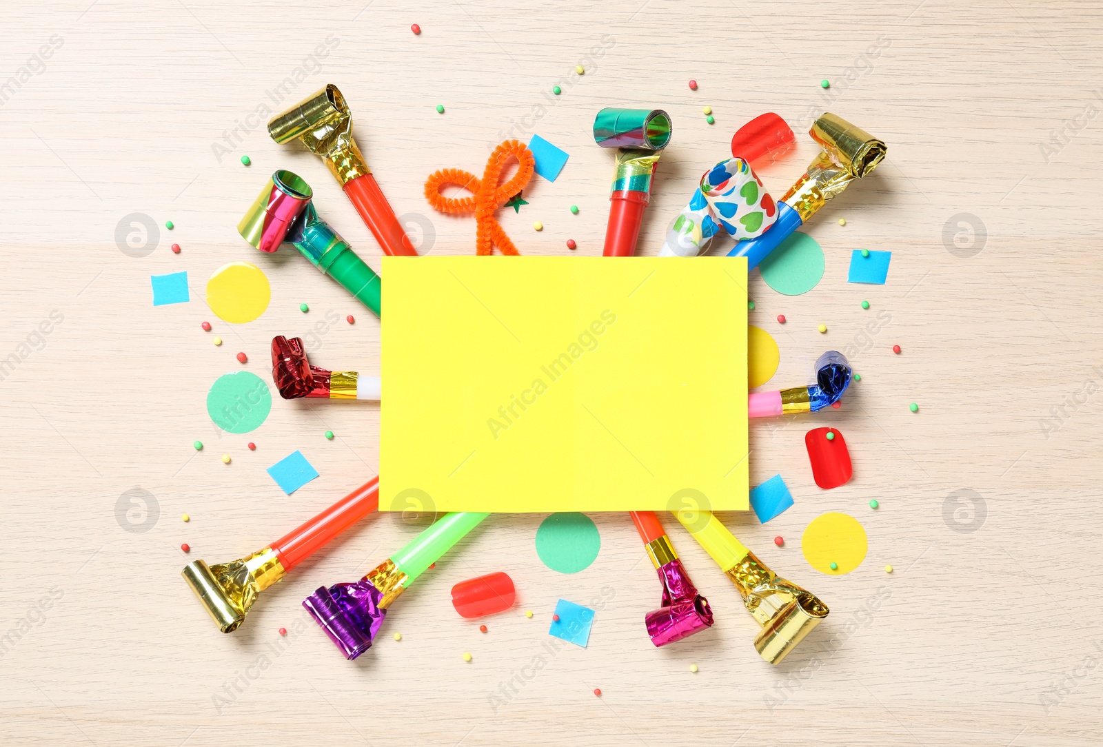 Photo of Flat lay composition with party blowers and blank card on wooden background. Space for text
