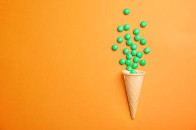 Photo of Flat lay composition with candies and ice cream cone on color background. Space for text
