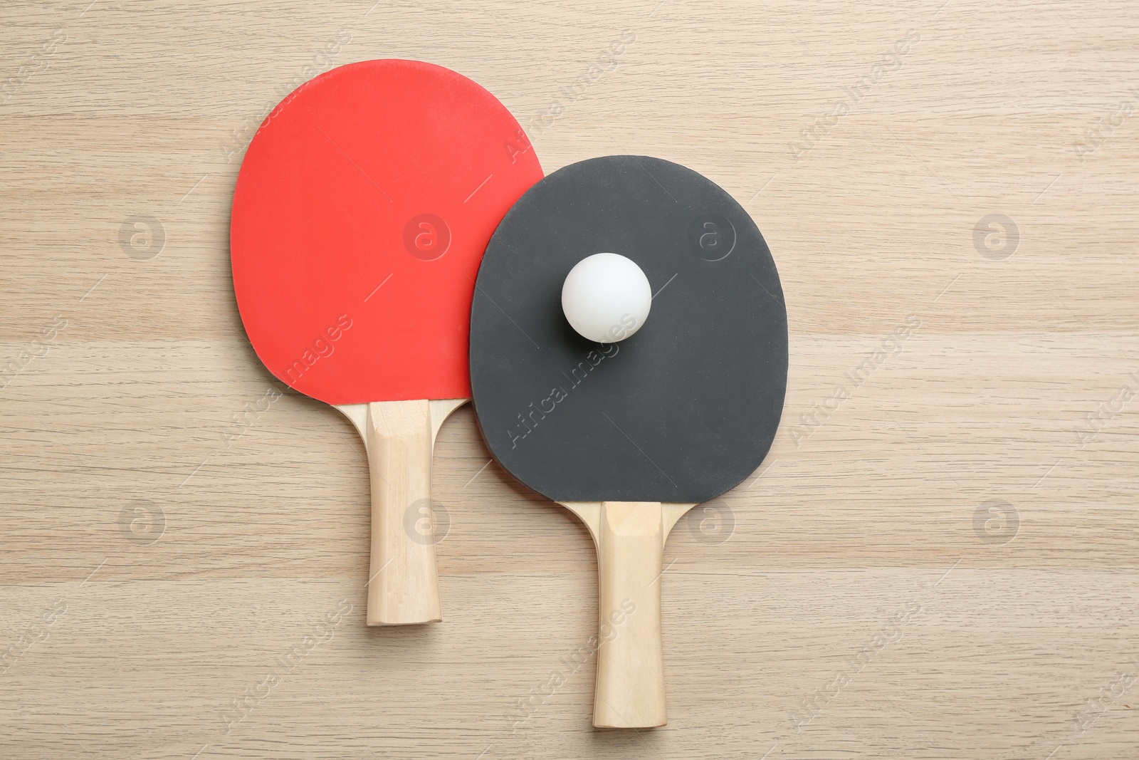 Photo of Ping pong rackets and ball on wooden table, flat lay