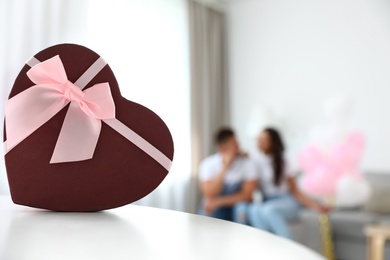 Photo of Beautiful heart shaped gift box and blurred couple on background. Space for text