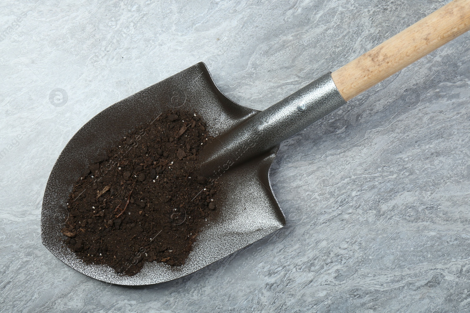 Metal shovel with fertile soil on gray textured surface, top view Photo of Metal shovel with fertile soil on gray textured surface, top view