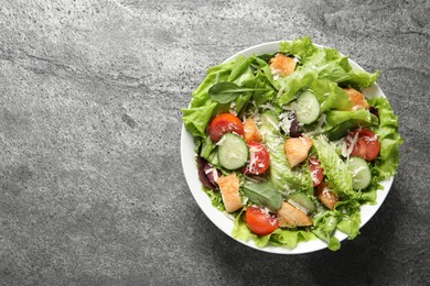 Delicious salad with chicken, cheese and vegetables on grey table, top view. Space for text