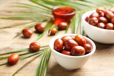 Photo of Palm oil fruits in bowl on wooden table, closeup