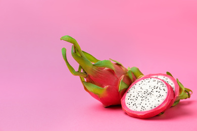 Photo of Delicious cut and whole dragon fruits (pitahaya) on pink background