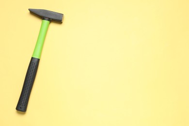 Photo of New hammer with rubber handle on yellow background, top view. Space for text