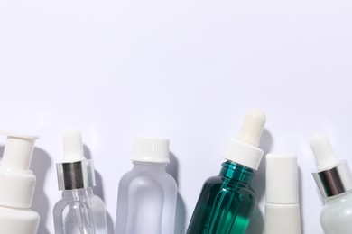 Photo of Many bottles of cosmetic serum on white background, flat lay. Space for text