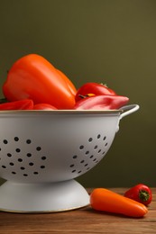 Photo of Colander with fresh vegetables on wooden table