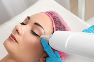 Photo of Woman undergoing laser tattoo removal procedure in salon, closeup