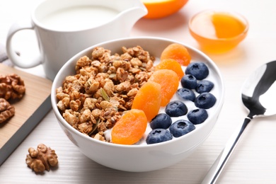 Photo of Delicious granola with fruits on white wooden table, closeup