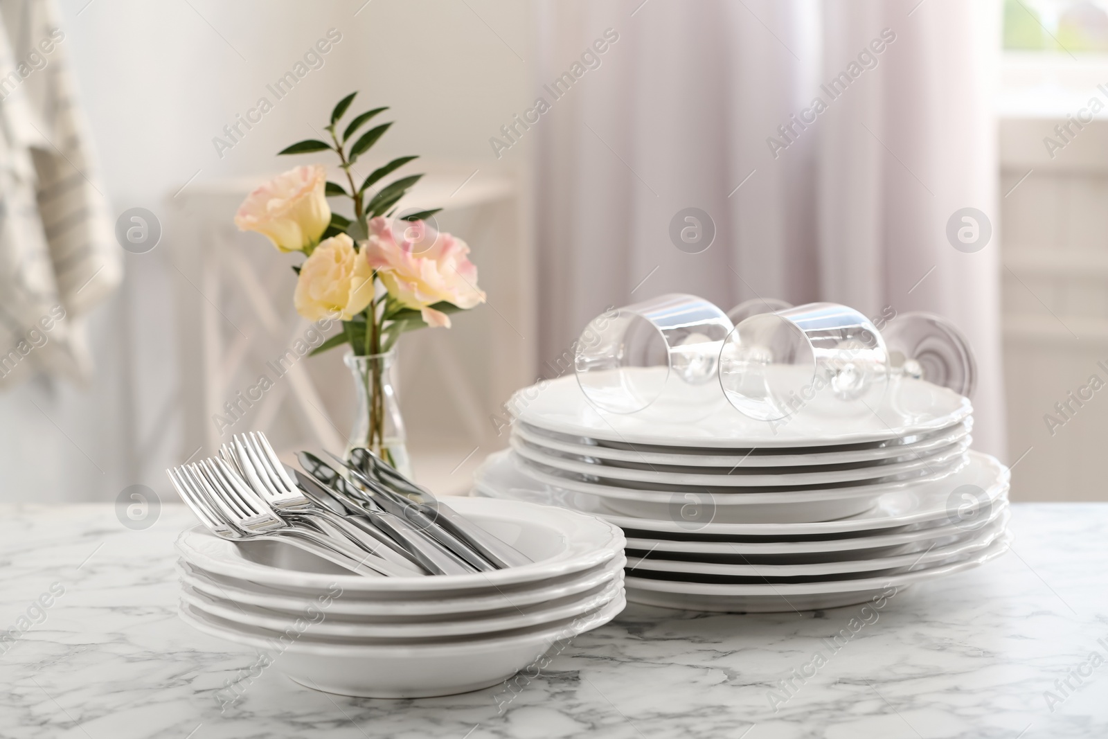 Photo of Set with clean dishes and vase of flowers on white marble table