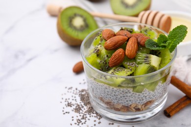 Photo of Delicious dessert with kiwi and almonds on white table, closeup. Space for text