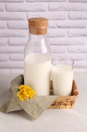Glass and bottle of fresh milk on table against white brick wall
