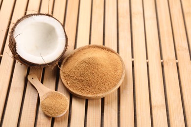 Photo of Coconut sugar, spoon, plate and fruit on wooden table, above view. Space for text