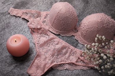 Elegant light pink women's underwear, candle and gypsophila flowers on grey background