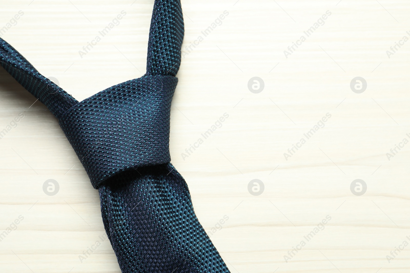 Photo of One blue necktie on white wooden table, top view. Space for text