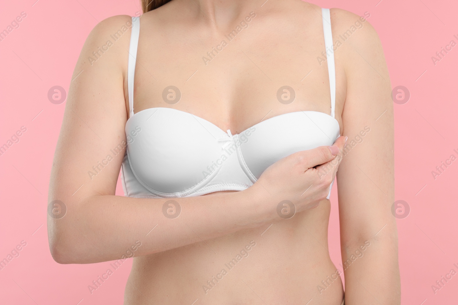 Photo of Mammology. Young woman doing breast self-examination on pink background, closeup