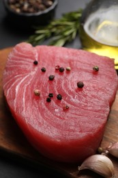 Raw tuna fillet with spices on wooden board, closeup
