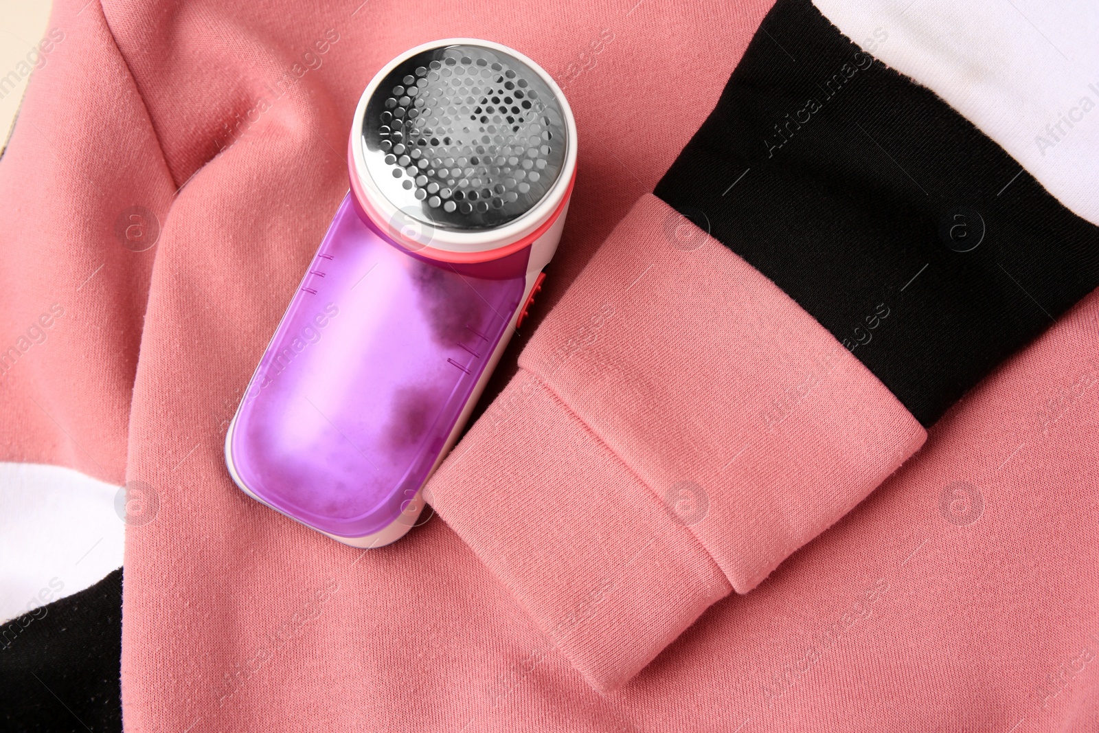 Photo of Modern fabric shaver on colorful sweater with lint, top view