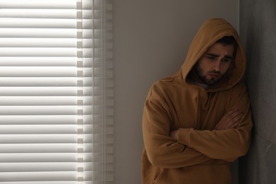 Photo of Sad young man at home. Space for text