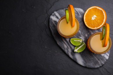 Photo of Fresh alcoholic Tequila Sunrise cocktails on black table, top view. Space for text