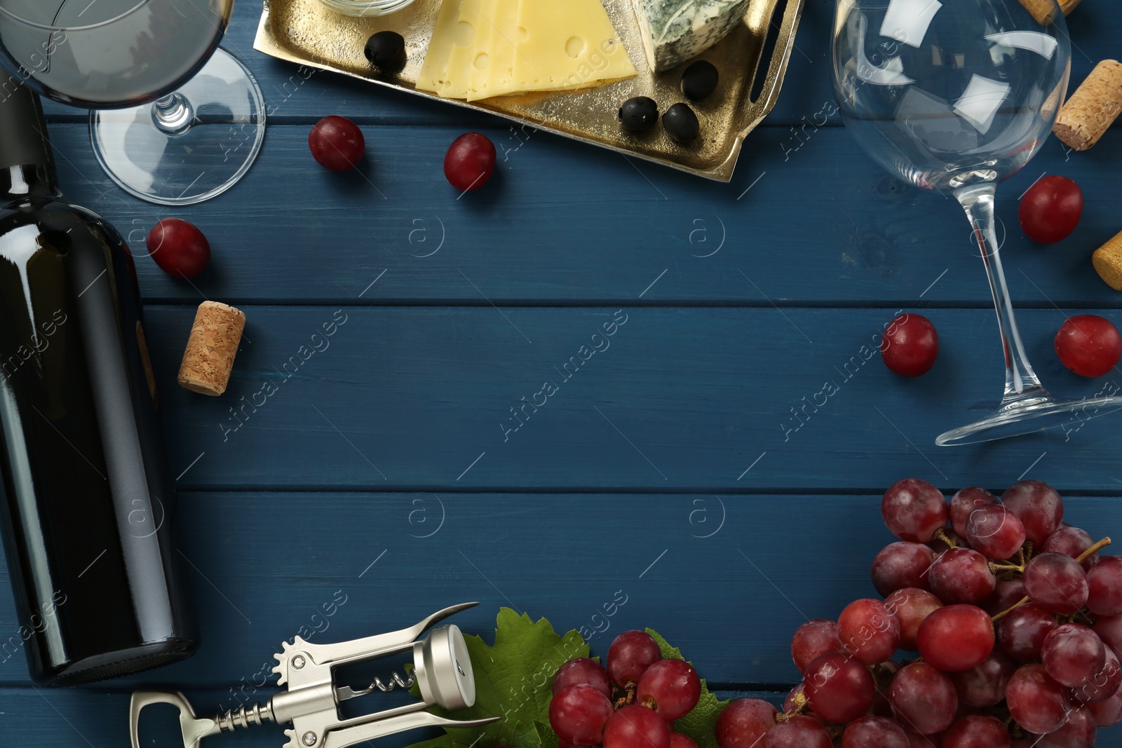 Photo of Flat lay composition with tasty red wine and grapes on blue wooden table, space for text