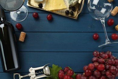 Flat lay composition with tasty red wine and grapes on blue wooden table, space for text