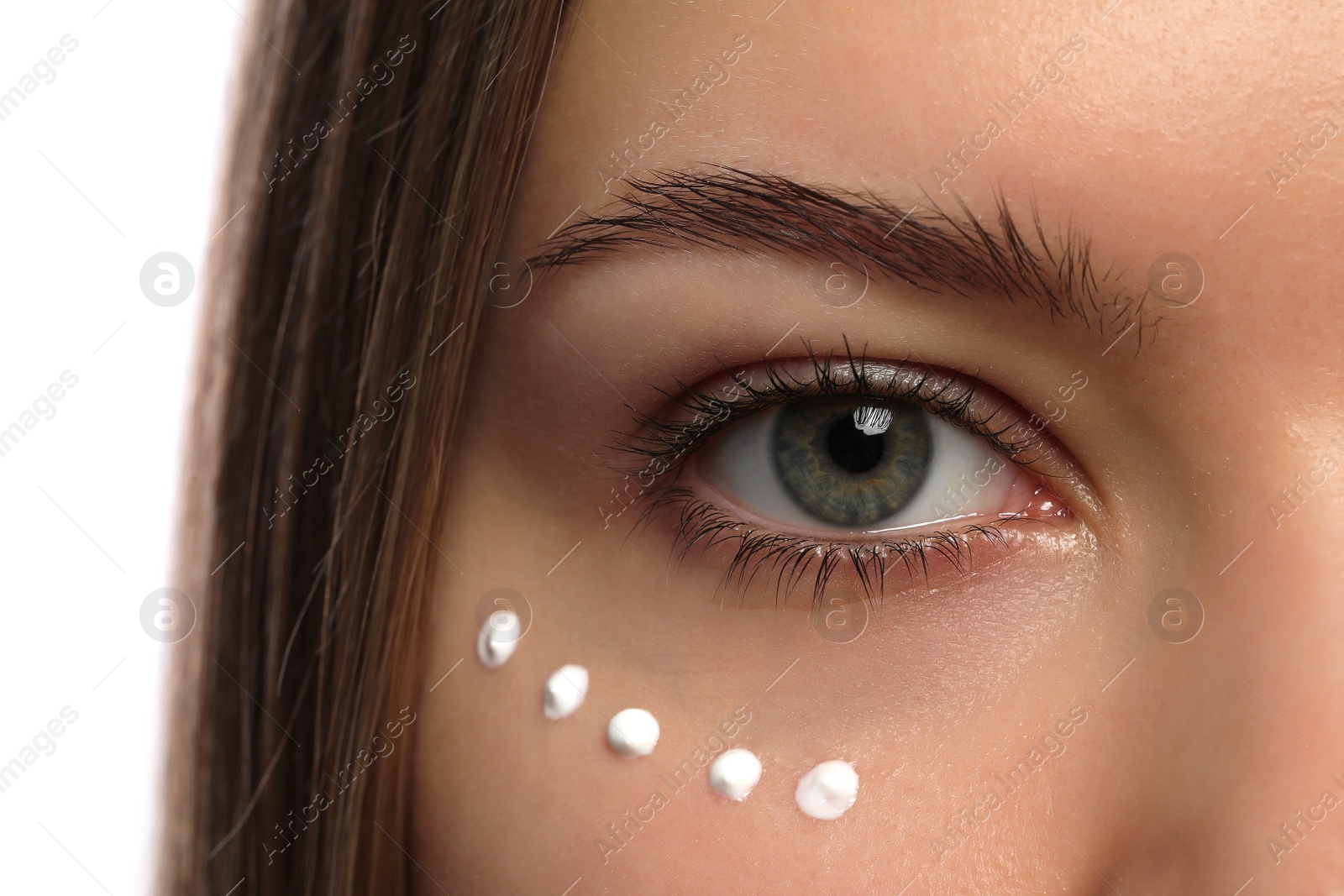 Photo of Young woman with cream around eye on white background, closeup