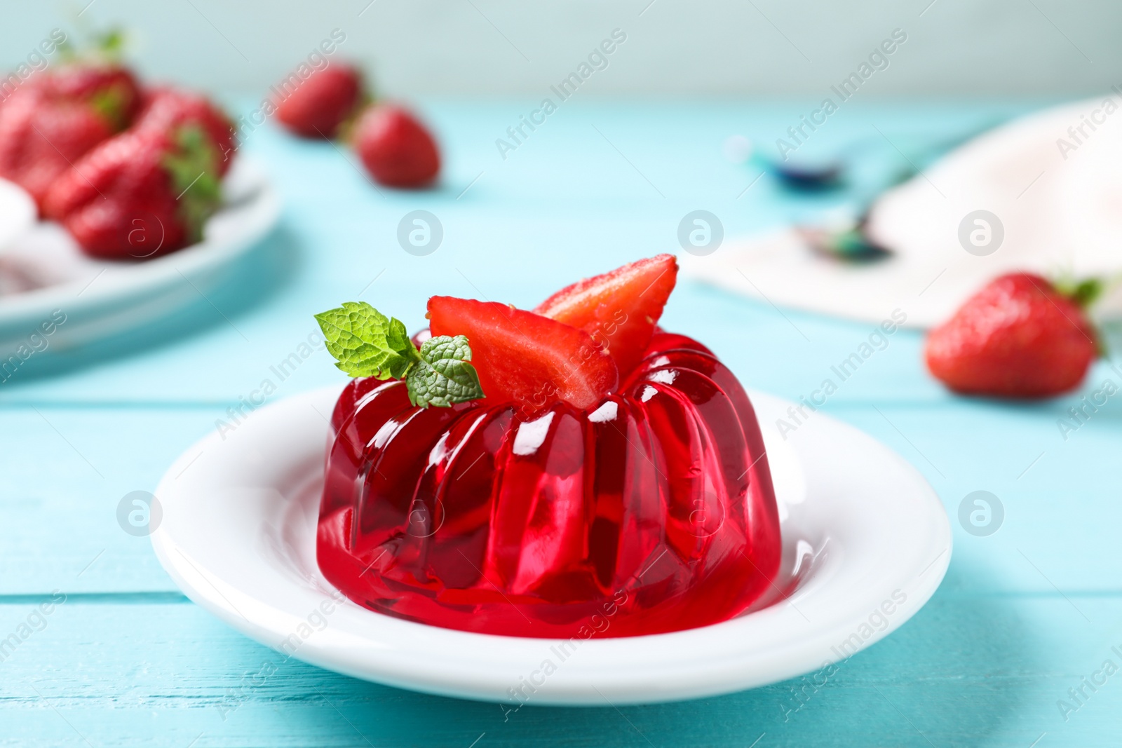 Photo of Delicious red jelly with strawberry and mint on light blue wooden table