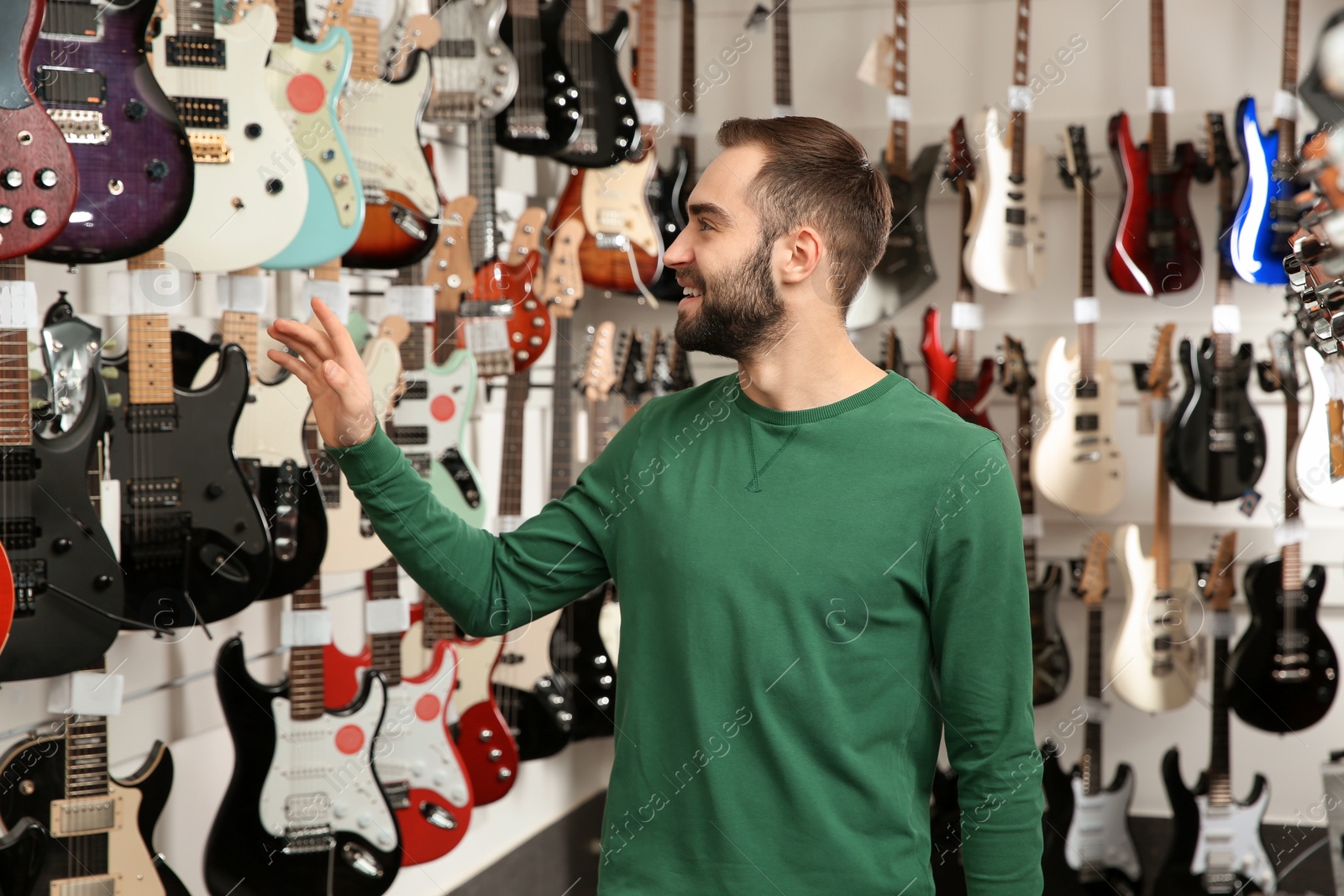 Photo of Buyer choosing guitar in modern music store