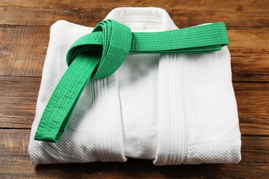 Photo of Green karate belt and white kimono on wooden background