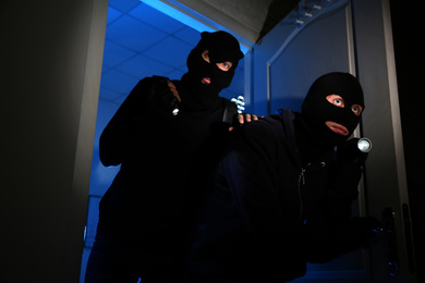 Photo of Thieves with flashlights breaking into house at night