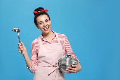 Photo of Housewife with pan and ladle on light blue background