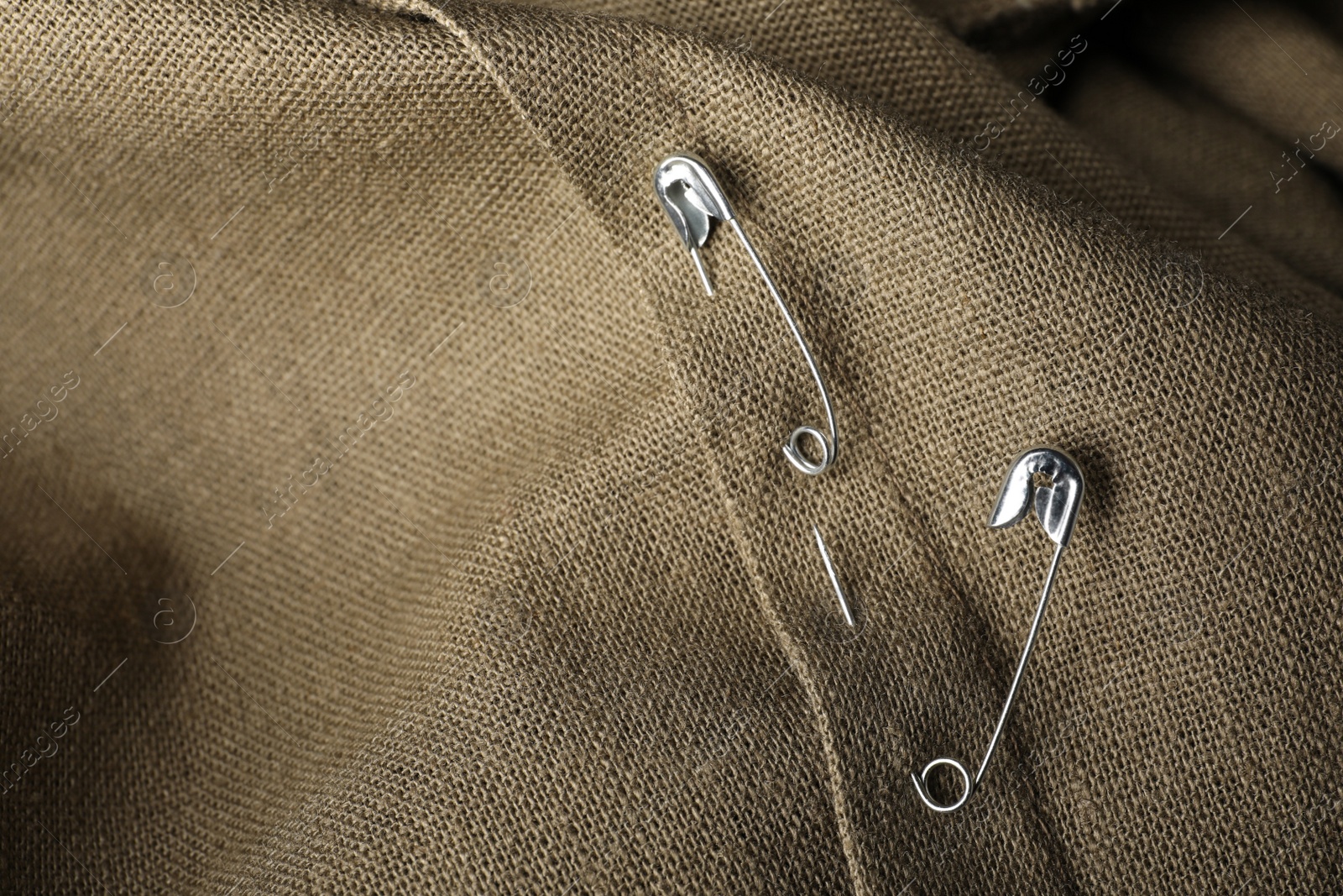 Photo of Metal safety pins on fabric, closeup view