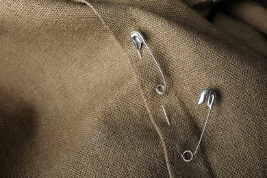 Photo of Metal safety pins on fabric, closeup view