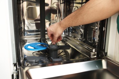 Photo of Repairman pulling drain filter out of dishwasher, closeup