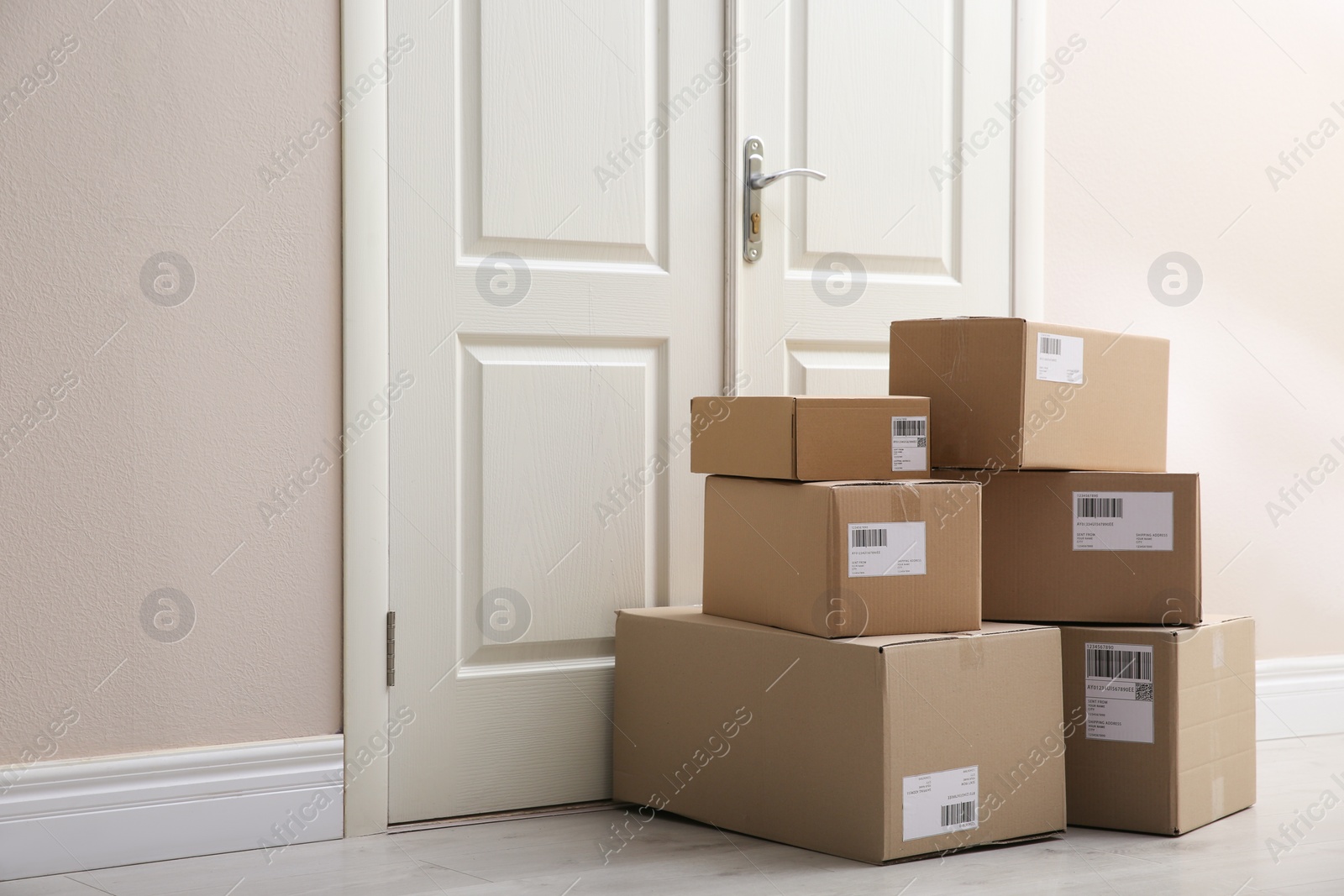 Photo of Stacked parcels near door on floor. Delivery service