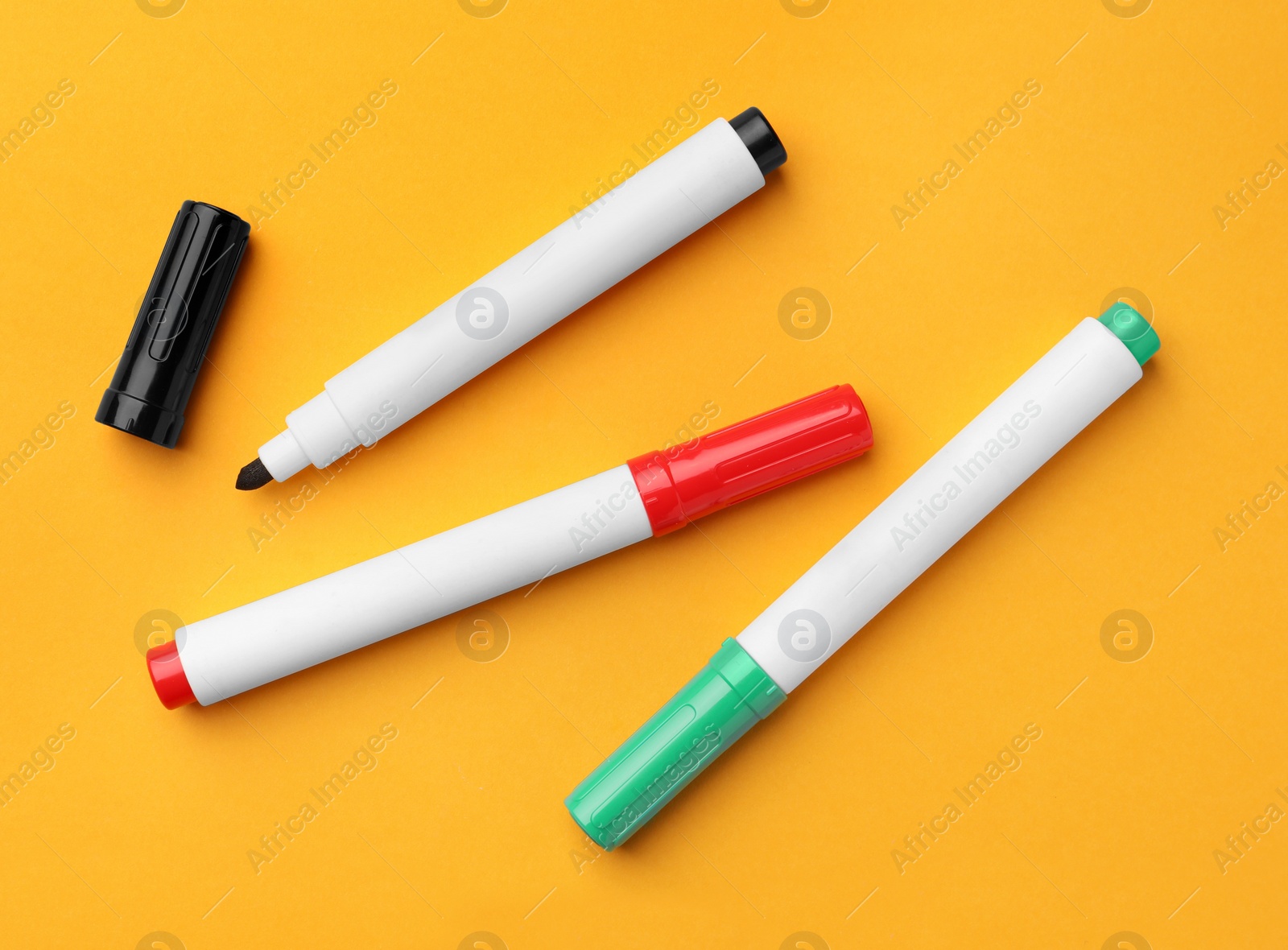 Photo of Bright color markers on orange background, flat lay