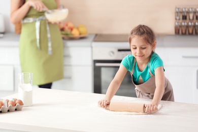 Mother and her daughter making dough at table in kitchen